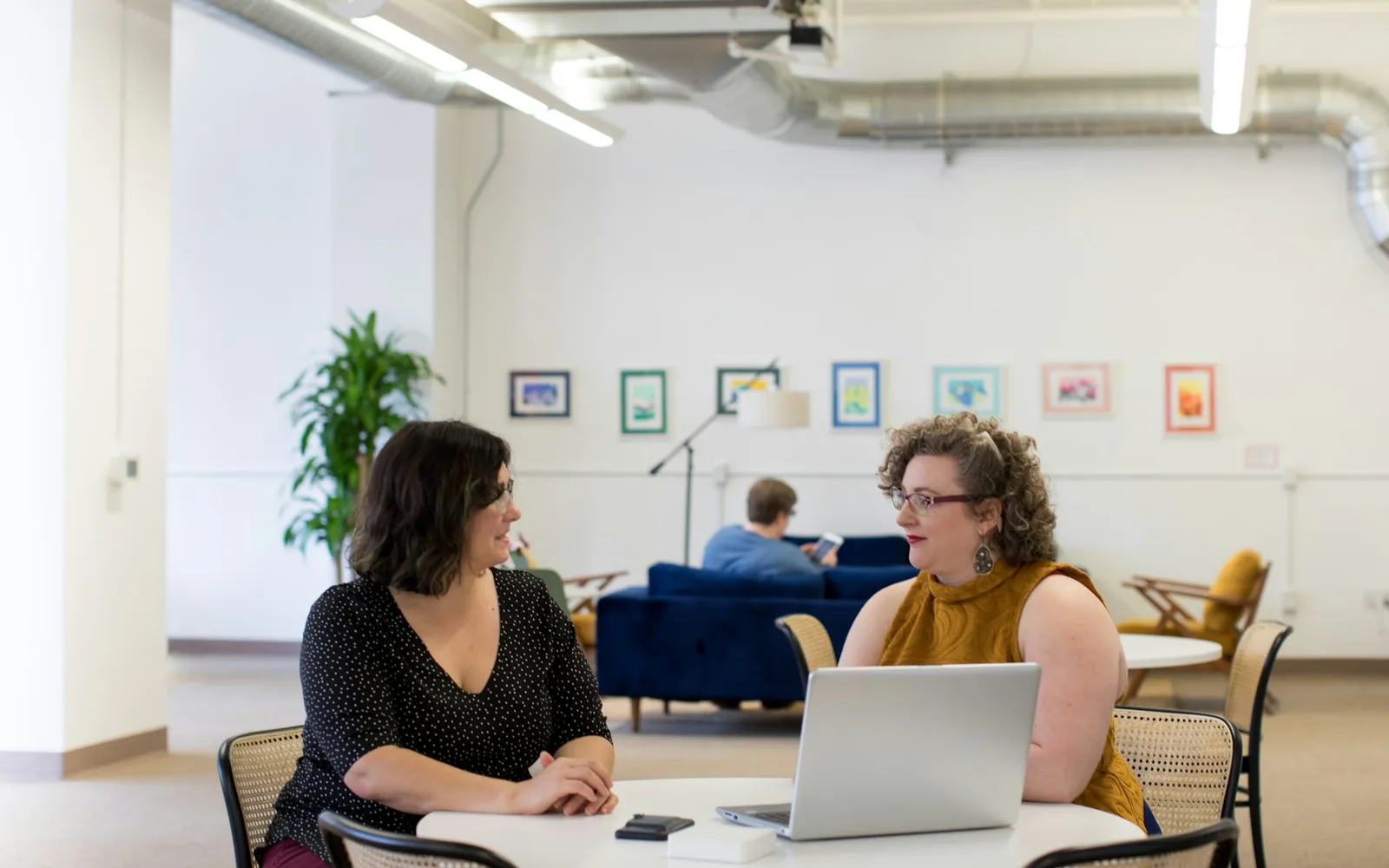 Two colleagues working through a problem at a laptop in a bright office