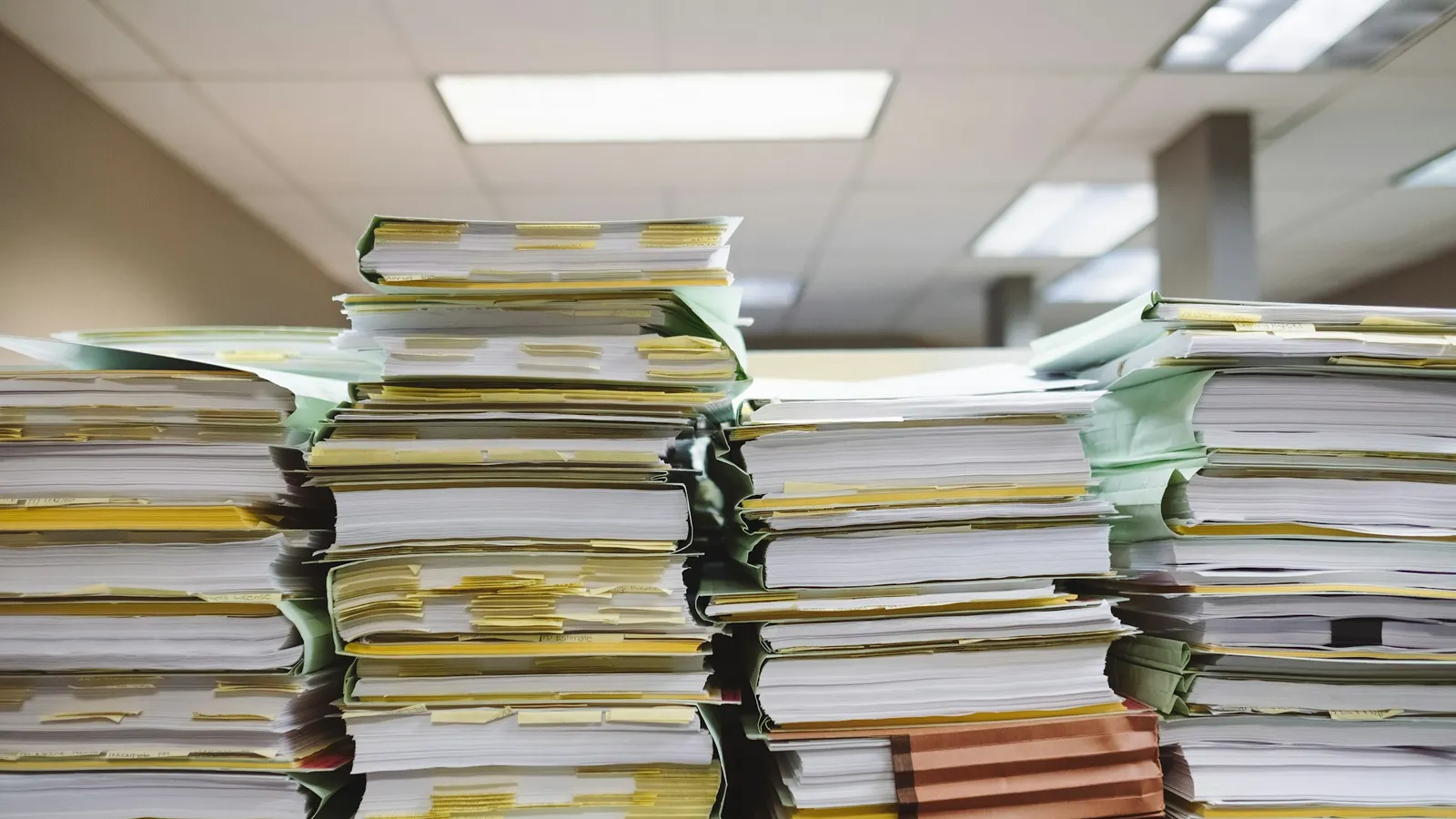 Stacks of paper documents and folders on a desk