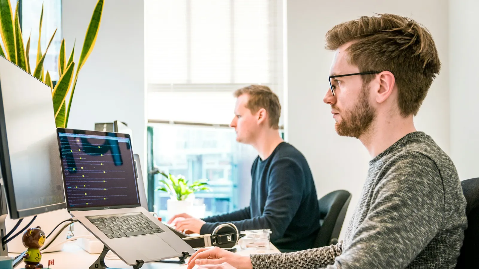 Two engineers at desks in a bright office