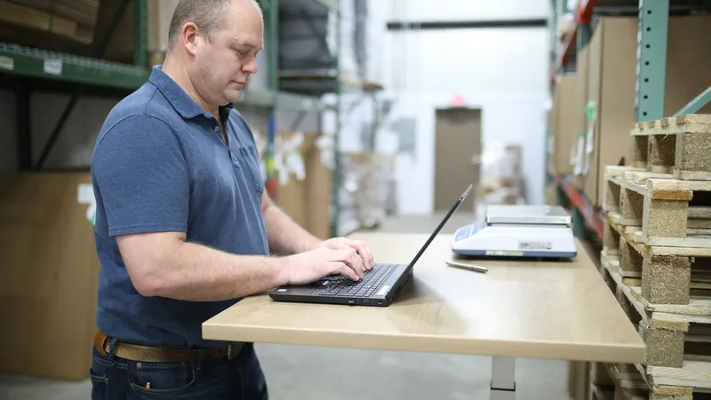 An operations manager working on a laptop in a warehouse